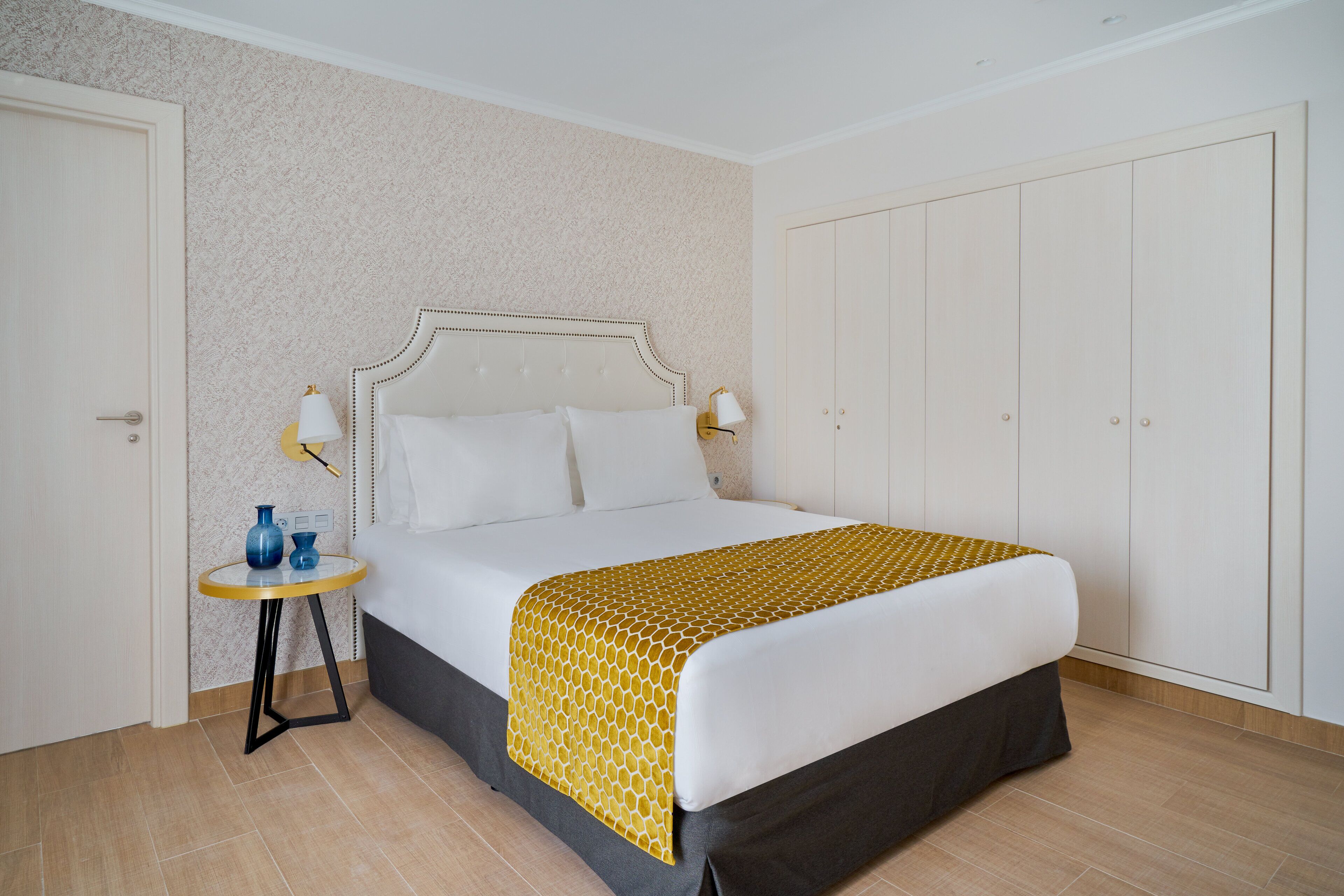 A neatly arranged hotel room with a bed, bedside tables, and a wardrobe.