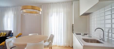 Una cocina moderna con encimera blanca, pileta de acero inoxidable y una lámpara colgante.