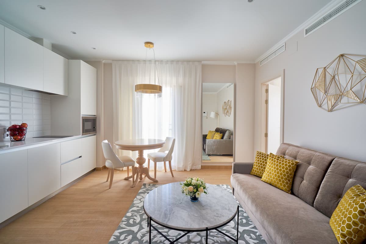 Una cocina moderna con armarios blancos, una mesa de comedor con sillas y una mesa redonda con un florero.