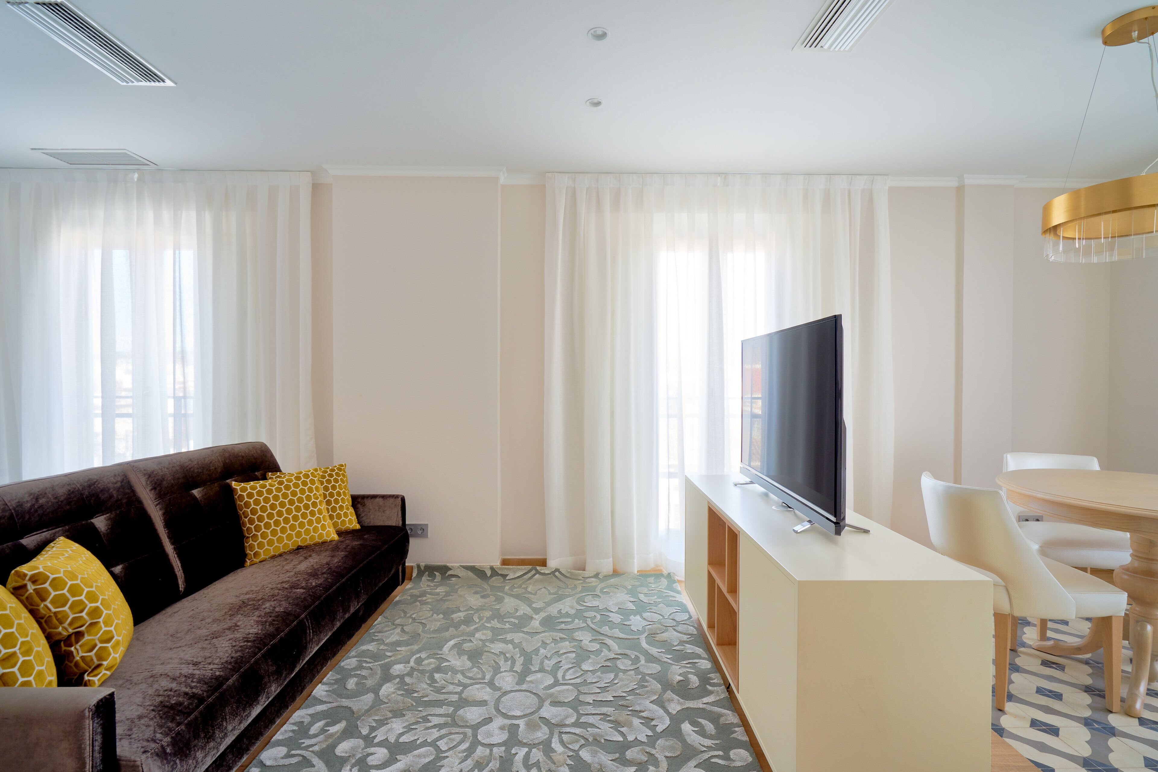 A modern living room with a sofa, TV, and dining area.