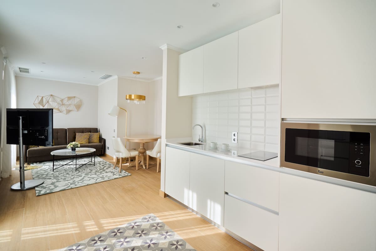 Una cocina moderna con armarios blancos, un microondas negro y un comedor con una mesa y sillas.