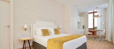A hotel room with a bed, bedside table, lamp, and a desk with chairs.