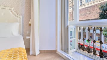 Een hotelkamer met een bed, een raam met uitzicht op een gebouw en een gordijn.