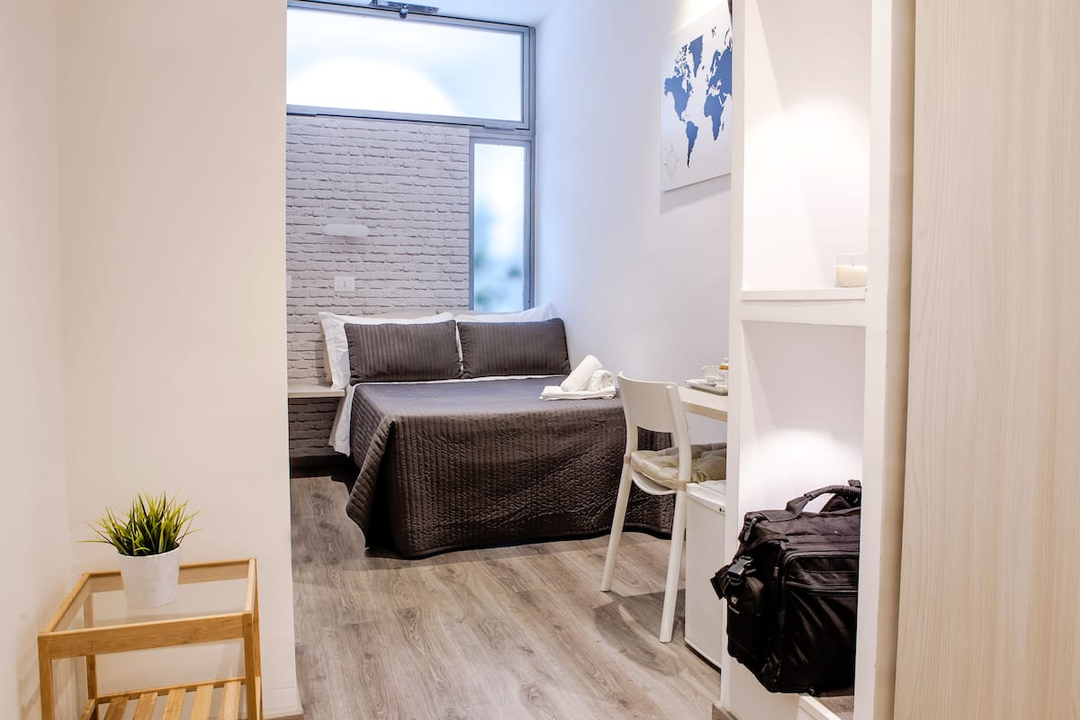 Ein kleines Zimmer mit einem Bett, einem kleinen Tisch, einem Stuhl und einem Schreibtisch.