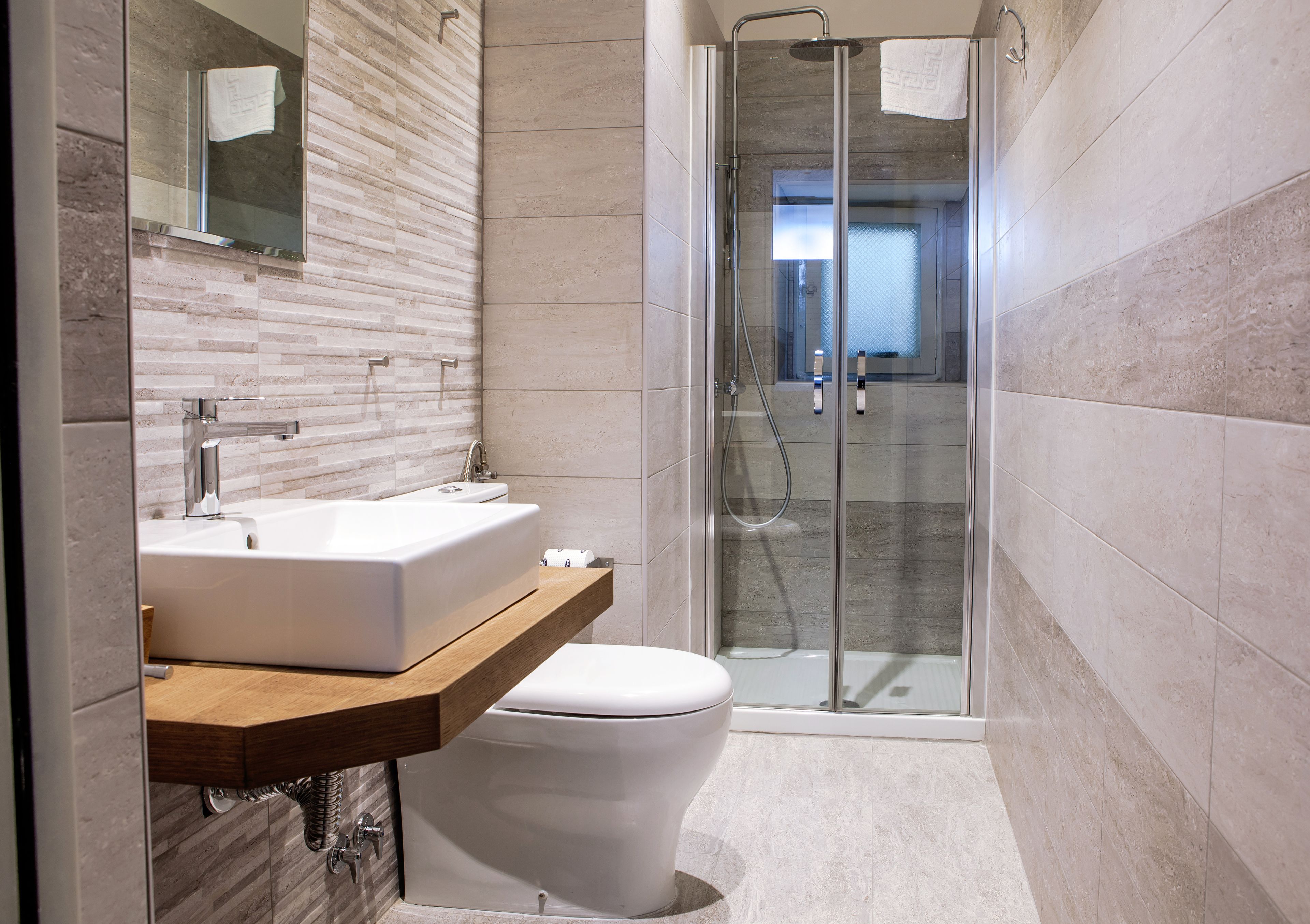 A modern bathroom with a glass shower enclosure, a wooden vanity, and a white toilet.