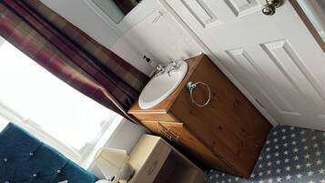 Un baño con un mueble de madera, un lavabo blanco y un espejo.