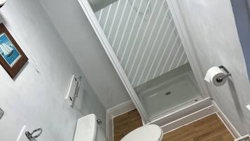 Une salle de bain avec un lavabo blanc, des toilettes et un espace douche.