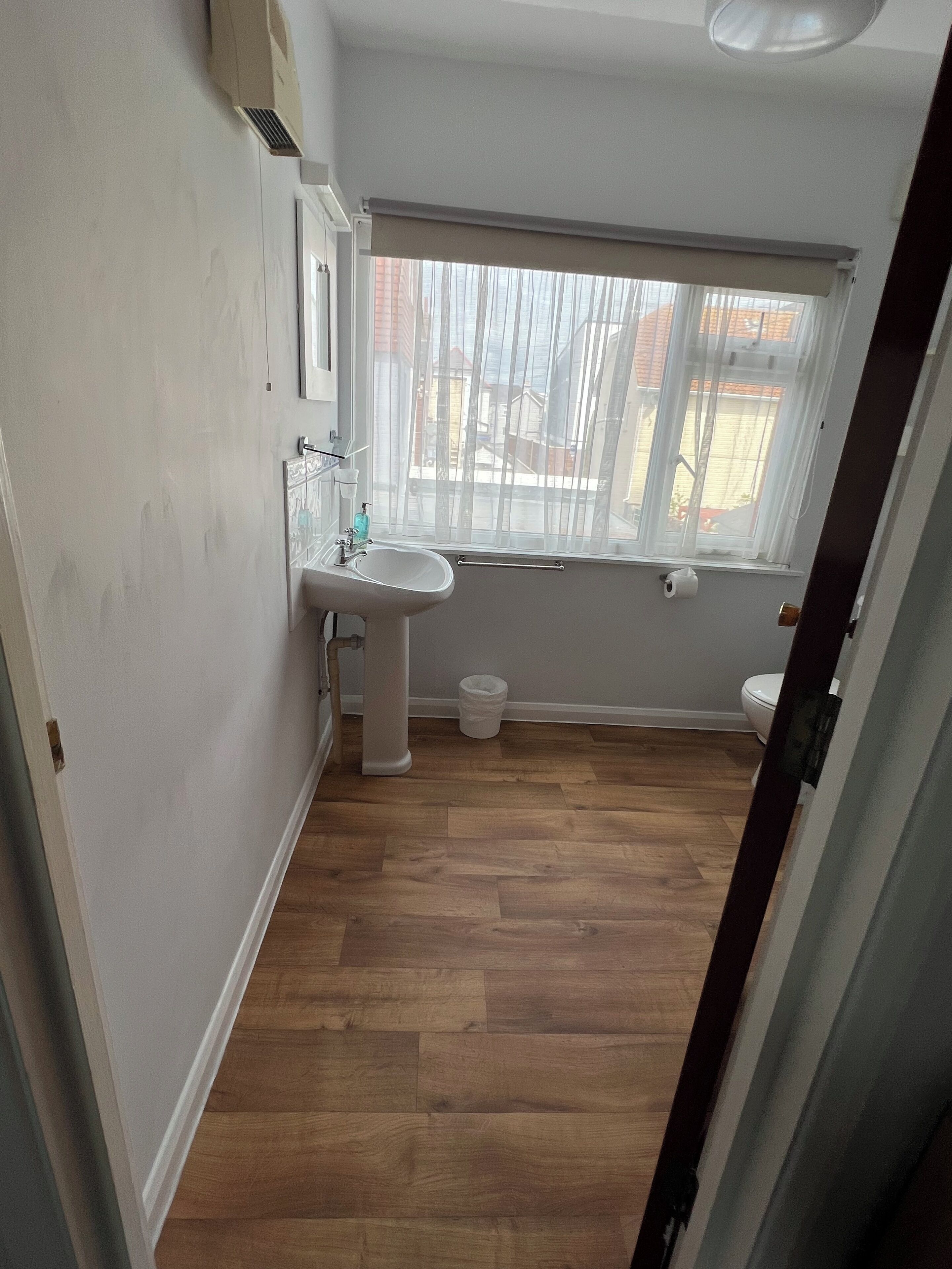 Un baño pequeño con lavamanos, inodoro y ventana.