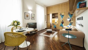 A modern living room with a dining area, wooden flooring, a sofa, a coffee table, and a TV. - Rome as you feel - Baccina 95 Forum Apartment (Rome)