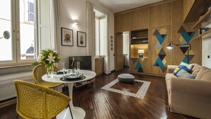 A modern living room with a dining area, wooden flooring, and a geometric-patterned wall. - Rome as you feel - Baccina 95 Forum Apartment (Rome)