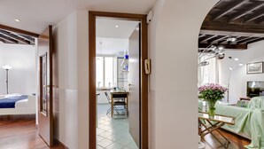 A modern interior with a wooden floor, a dining area with a table and chairs, and a kitchen in the background. - Rome as you feel - Panisperna Apartment (Rome)
