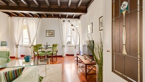 A spacious living room with a glass coffee table, a sofa, and a dining area with chairs and a table. - Rome as you feel - Panisperna Apartment (Rome)