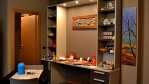 A kitchenette with a dining area, a buffet setup, and a painting on the wall. - Chambres D'Hotes La Bicoque (Sarre)