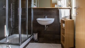 A modern bathroom with a glass-enclosed shower, a white sink, and a wooden vanity. - Chambres D'Hotes La Bicoque (Sarre)