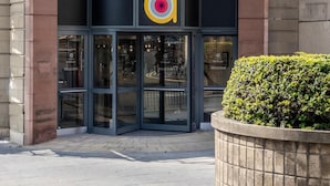 L’extérieur d’un hôtel, avec une entrée incurvée, de grandes portes vitrées et un logo au-dessus de l’entrée.