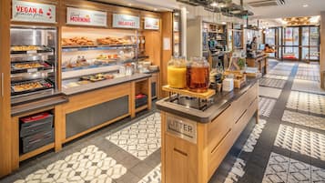 A breakfast bar with vegan and gluten-free options, a coffee machine, and a beverage dispenser.