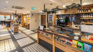 Un espace bar moderne doté d’un comptoir, de sièges et offrant un large choix de boissons.