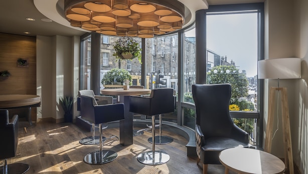 Un intérieur moderne avec une table ronde, des tabourets de bar et une grande fenêtre donnant sur la ville.