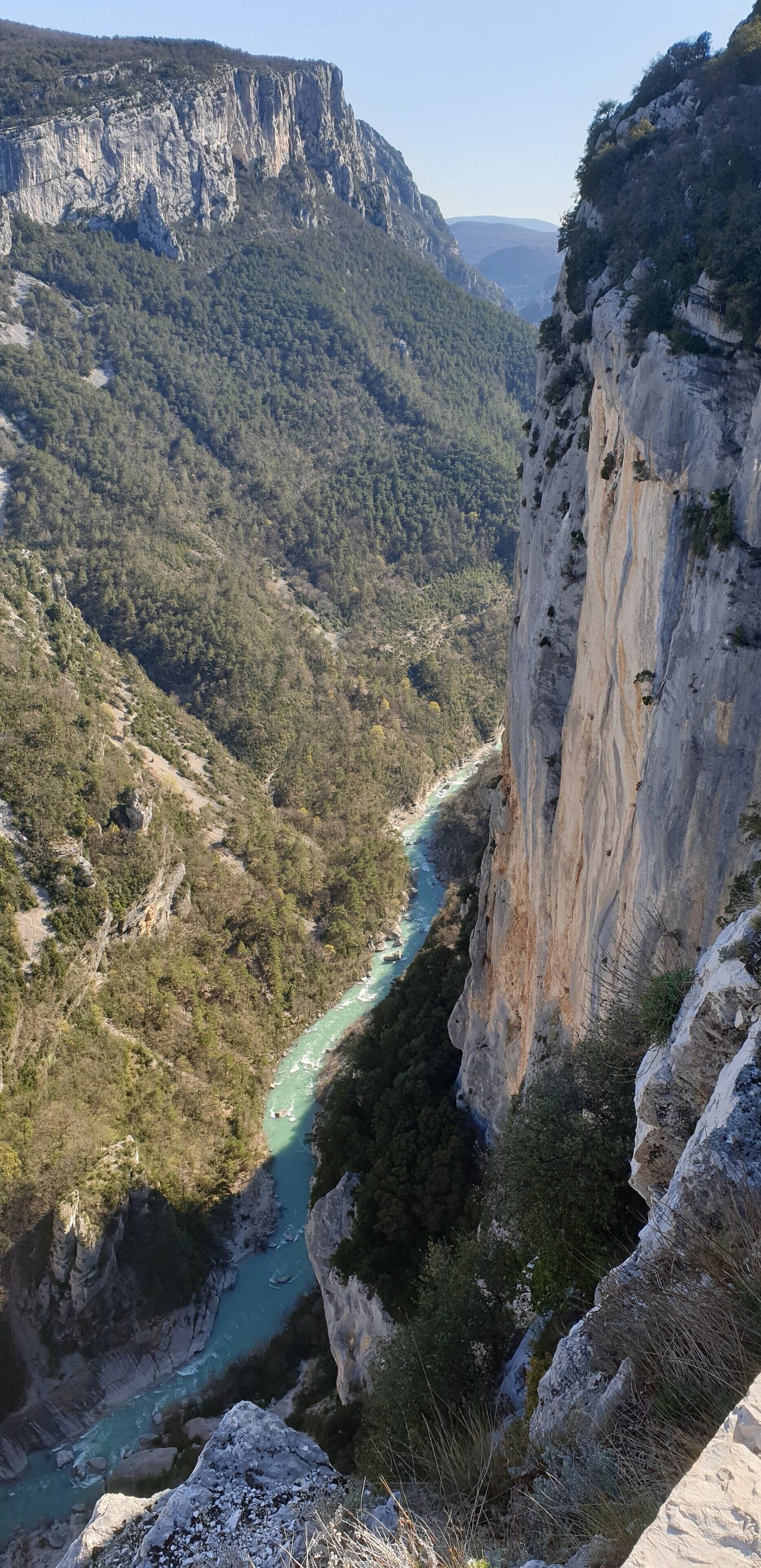 Ein Fluss fließt durch ein gebirgiges Tal mit steilen Felswänden an einer Seite.