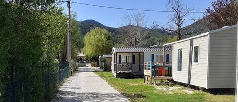 A gravel path leading to mobile homes with a grassy area and trees on one side.