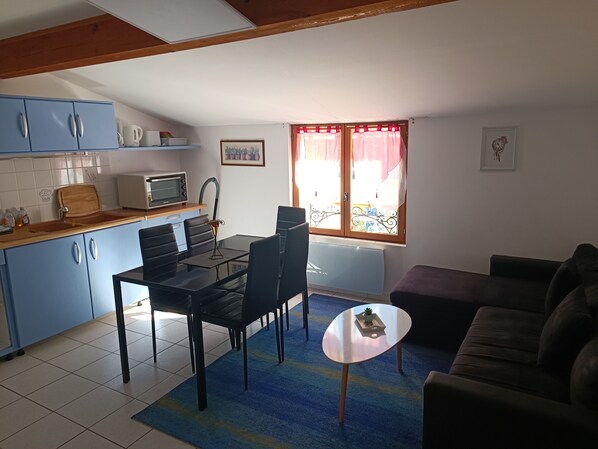 Un espacio habitable compacto con kitchenette, comedor y zona de estar.