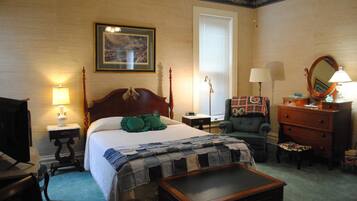 A hotel room with a bed, a chair, a dresser, a desk, and a lamp.