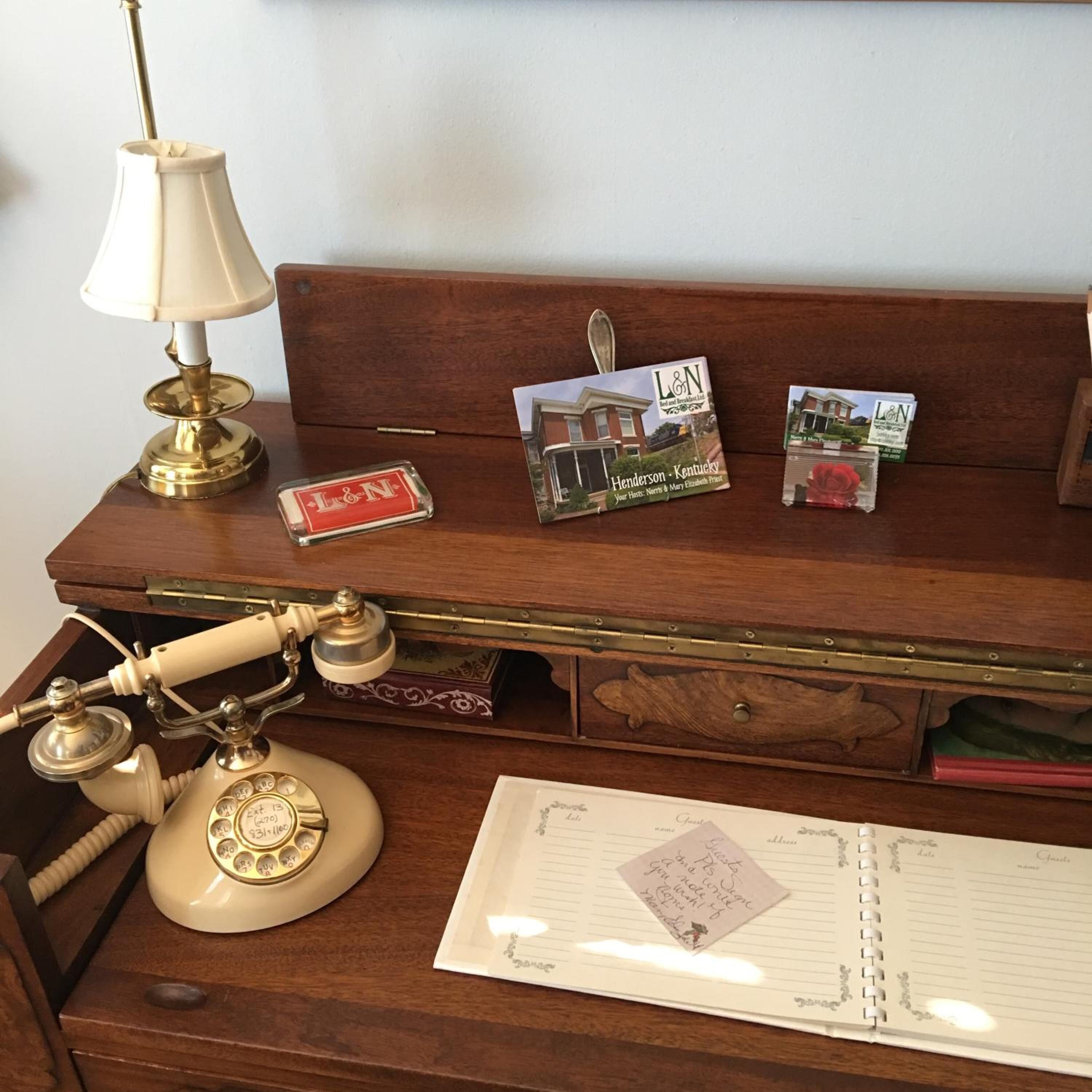 Un bureau en bois, sur lequel on trouve un téléphone d’époque, une lampe et un carnet.