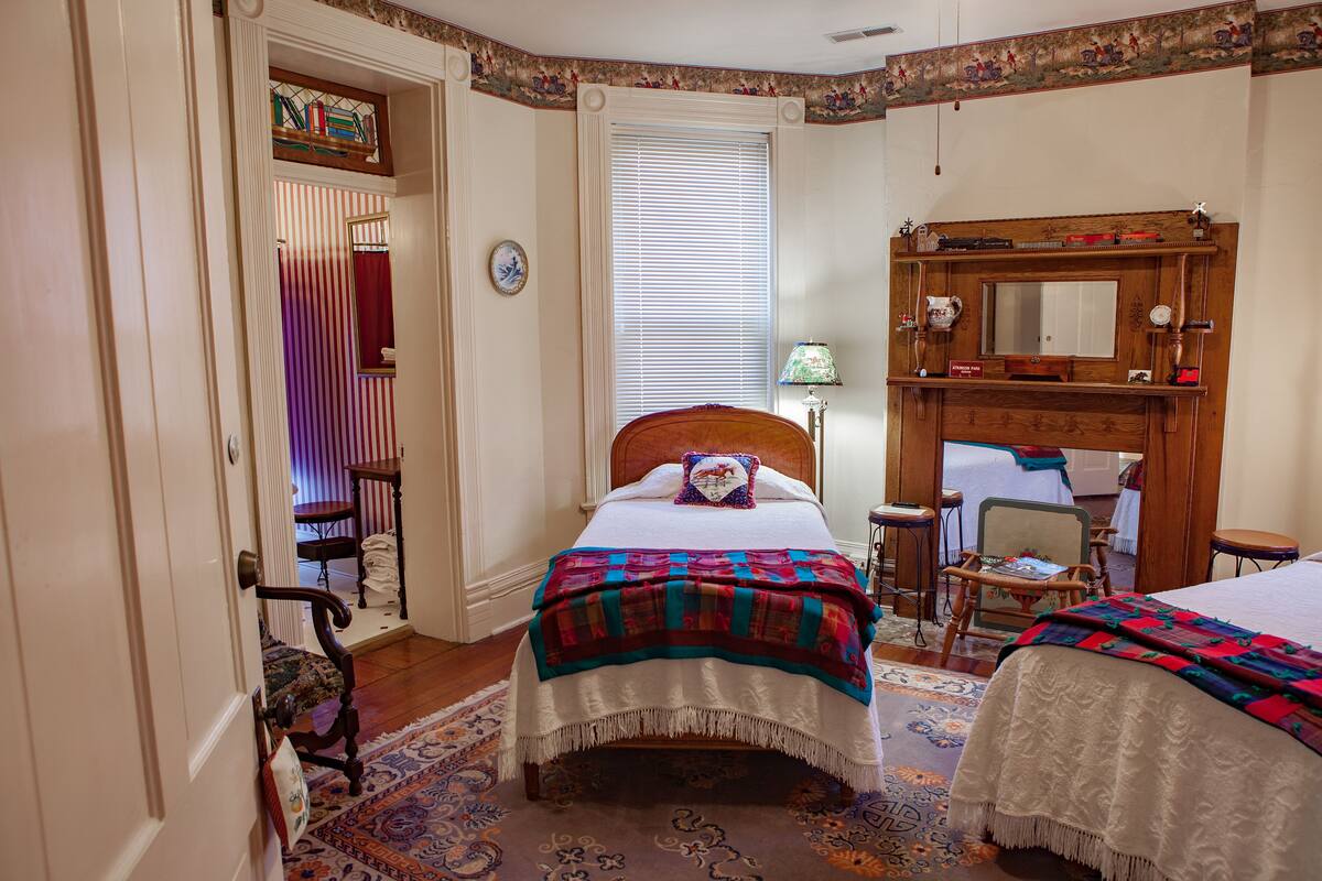 A bedroom with a bed, a chair, a desk, and a mirror.