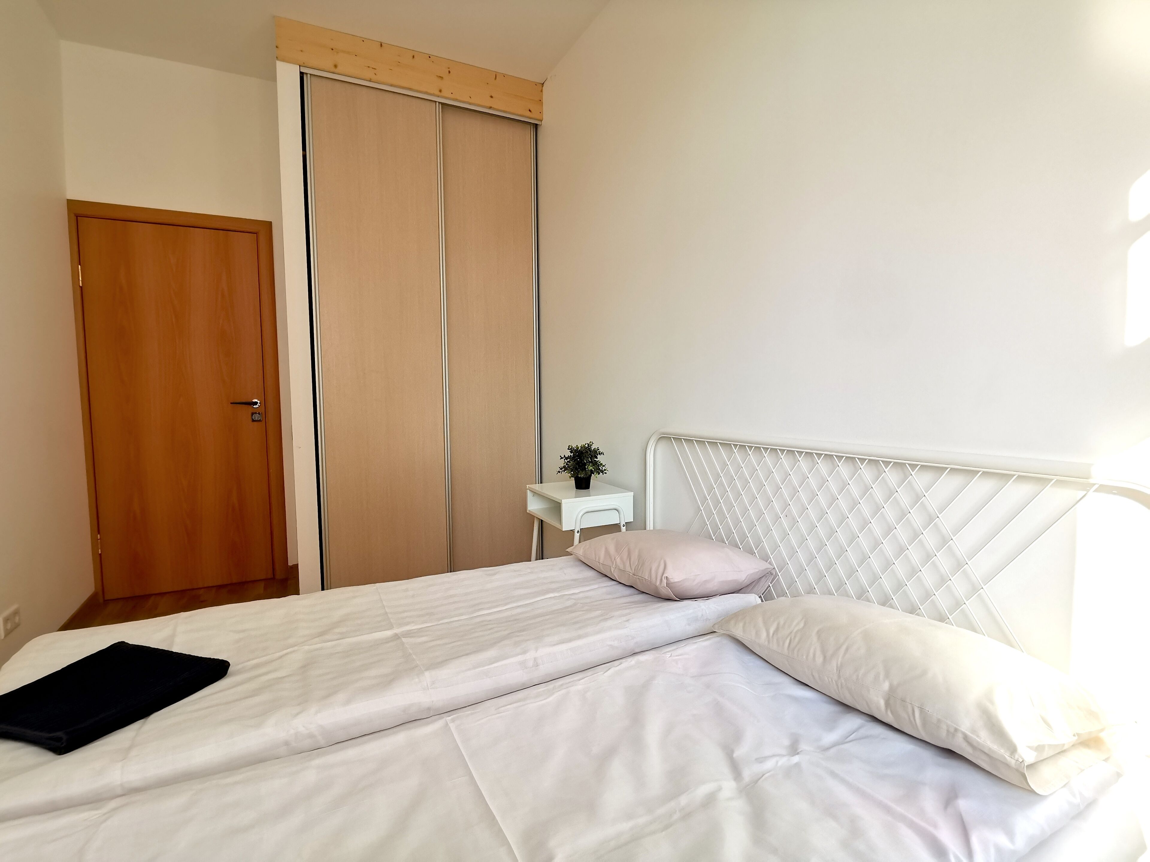 A bedroom with a bed, a wooden door, and a sliding closet door.