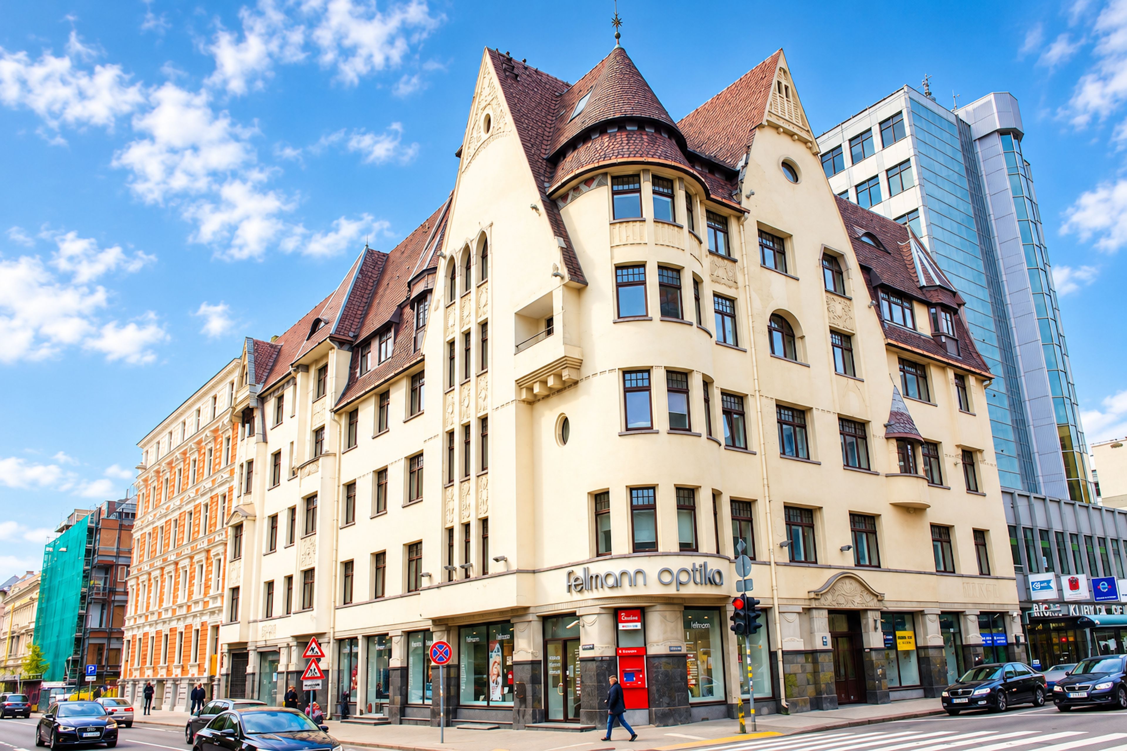 A multi-story building with a classical architectural style, featuring a prominent corner turret and a ground-level entrance with a storefront.
