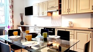 Una cocina moderna con una mesa de comedor de vidrio, armarios de madera y un televisor de pantalla plana sobre la encimera.