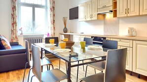 Una cocina moderna con armarios blancos, una mesa de comedor con sillas y un sofá en la zona de estar contigua.