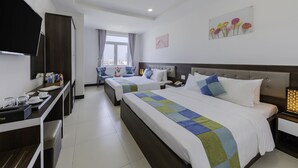 A hotel room with two beds, a desk with a flat-screen TV, a window with curtains, and a wall-mounted artwork of flowers. - Phuc Thanh Hotel (Da Nang)