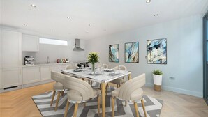 A modern kitchen with white cabinetry, a built-in oven, and a coffee machine. - Rainsford Mews by Lime Street (London)