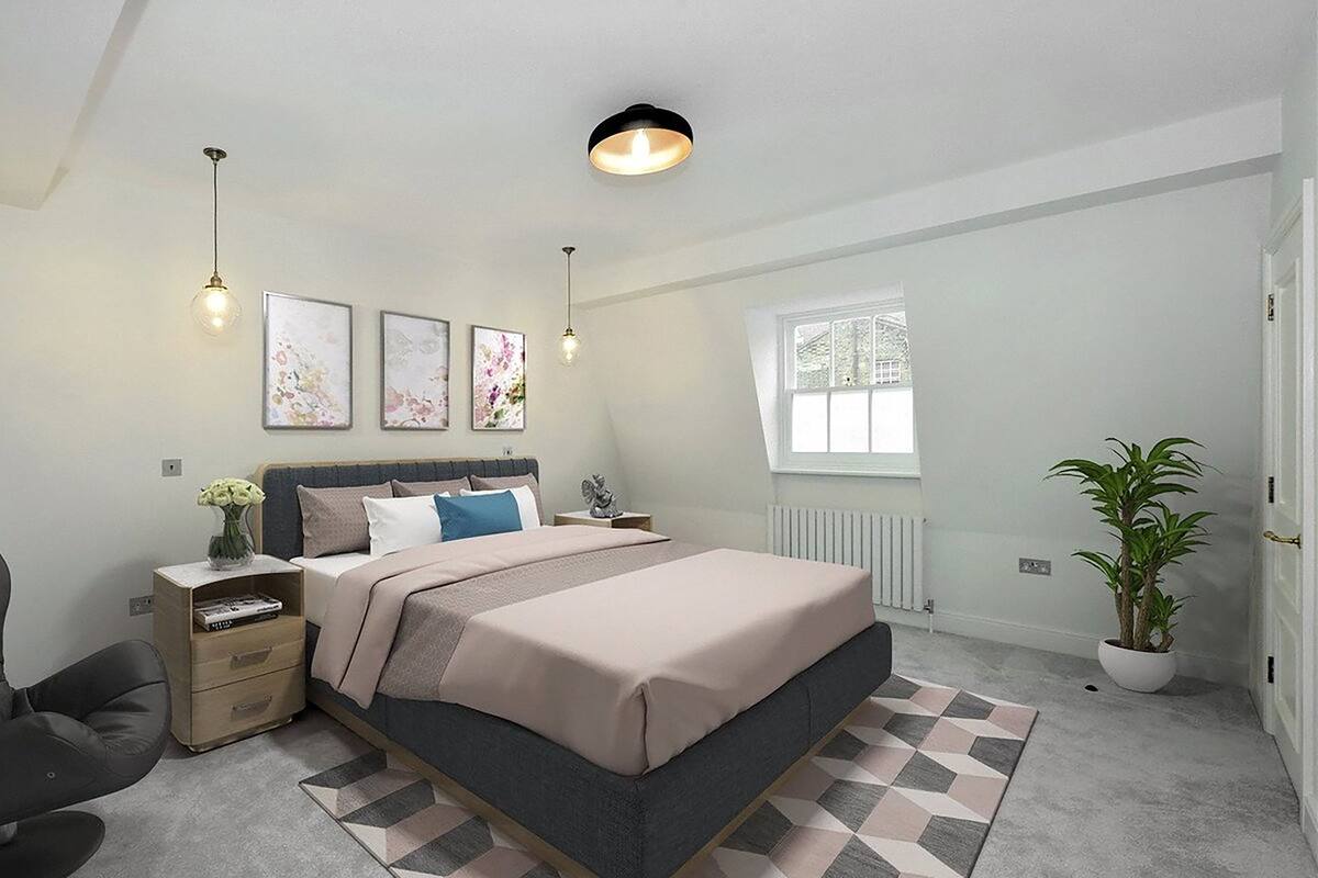 A bedroom with a bed, bedside tables, a chair, a radiator, a window, and a potted plant.