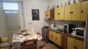 A compact kitchen with a dining table, chairs, and basic appliances. - B&B Mamoiada Centro (Mamoiada)