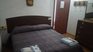 A bedroom with a dark brown headboard, a bed with a quilted cover, and a wooden dresser with a mirror. - B&B Mamoiada Centro (Mamoiada)