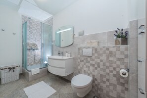A modern bathroom with a glass shower enclosure, a white sink, and a toilet.