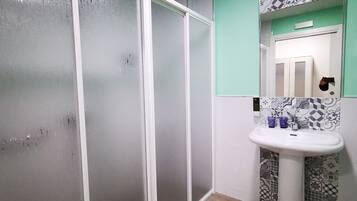 Un baño con lavamanos blanco, baldosas estampadas, un espejo y una puerta con secador de pelo en la pared.