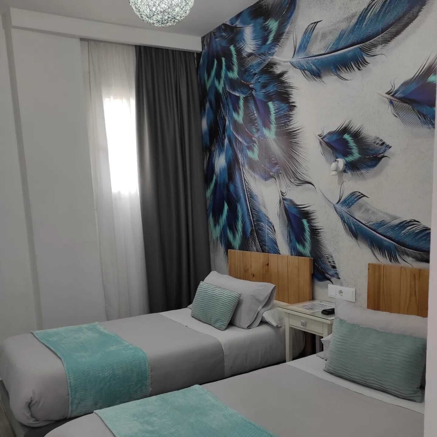 Ein Hotelzimmer mit zwei Betten, einem Nachttisch und einem Wandbild mit Federn.