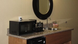 Una kitchenette compacta equipada con microondas, cafetera y lavabo.