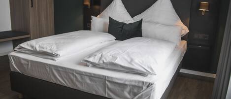 Habitación de hotel moderna con una cama grande, dos mesitas de noche y un cabecero oscuro.