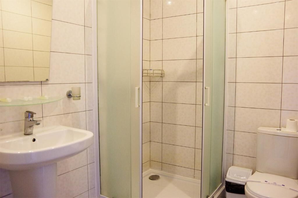A bathroom with a glass-enclosed shower, a sink, and a toilet.