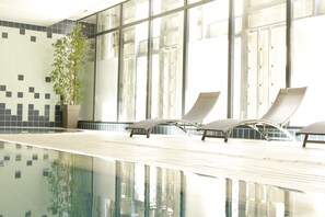 Una piscina techada, sillones reclinables de piscina