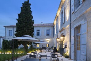 A courtyard with outdoor seating, a large tree, and a building with a light-colored facade and shutters. - Hotel College des Doctrinaires, BW Premier Collection (Lectoure)