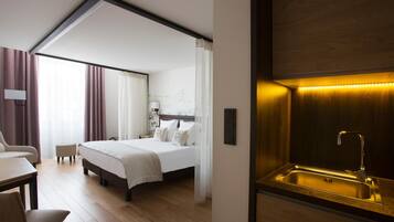 Una camera d'albergo moderna con un letto grande, una scrivania e un angolo cottura integrato con lavandino.