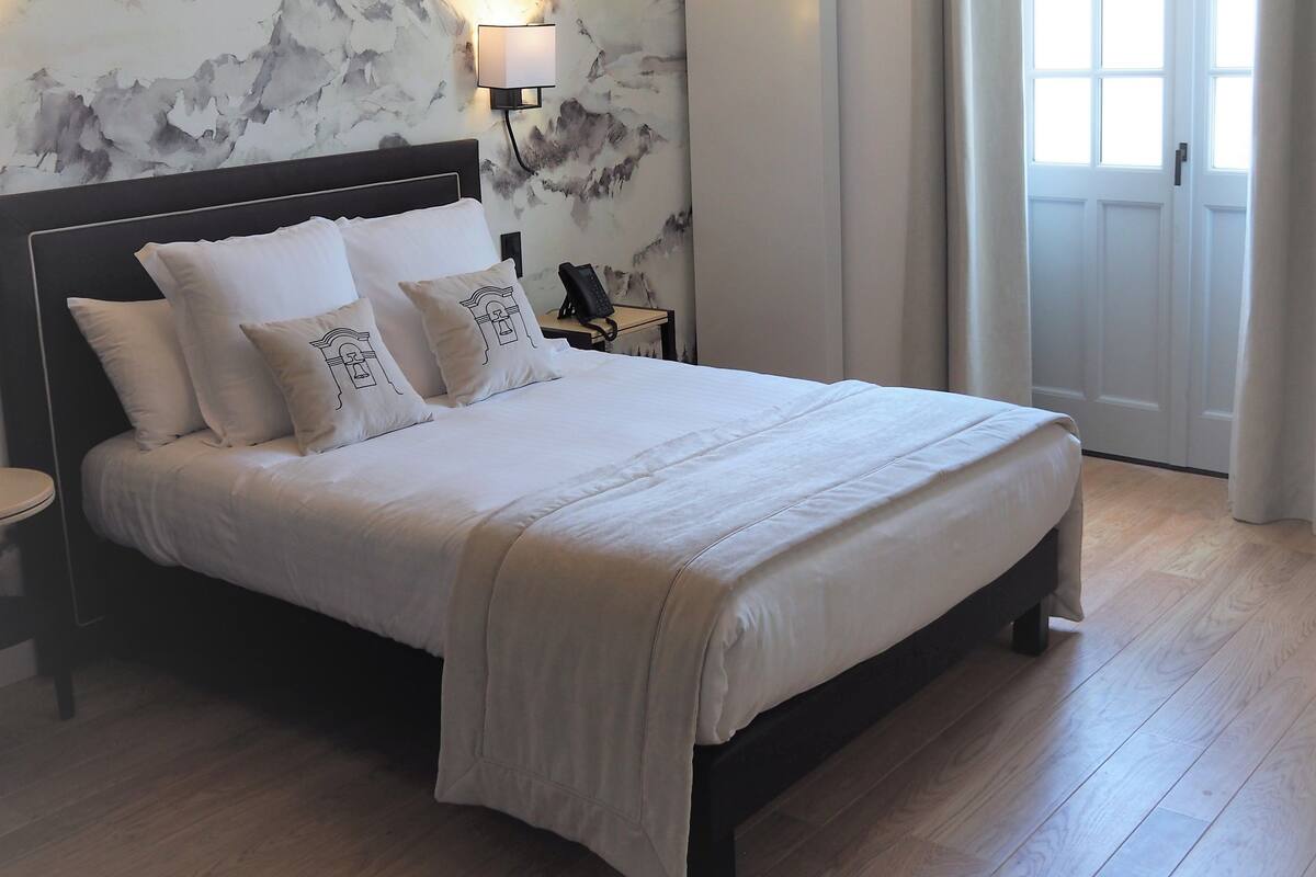 A neatly made bed with a headboard, a bedside lamp, and a wall-mounted light fixture.