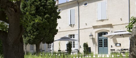 Un bâtiment avec un grand arbre au premier plan, une pelouse bien entretenue et un ciel dégagé.