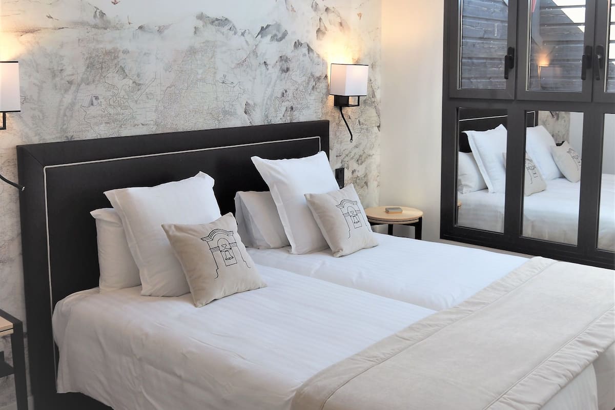 A double bed with white bedding, a skylight, and a wall with bird decals.