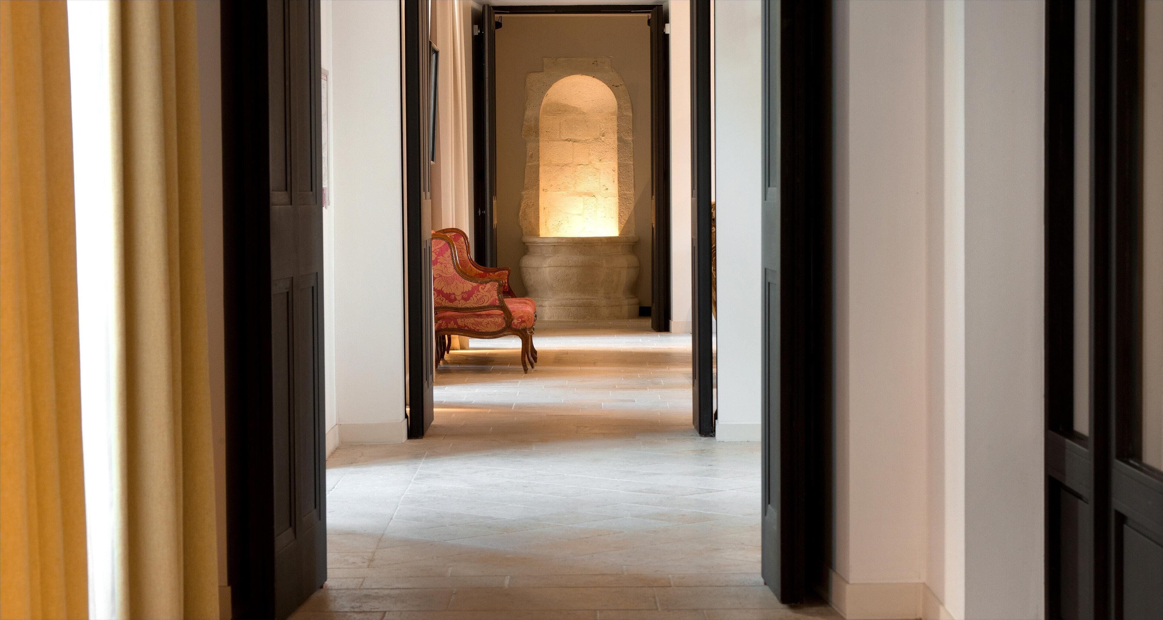 A hallway with a stone wall, a wooden door, and a red upholstered chair.